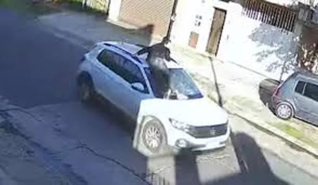 El joven sobre el capó del auto.